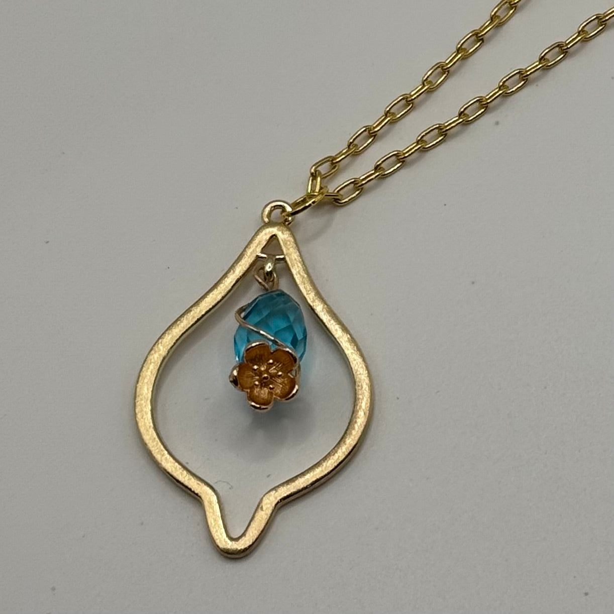 Gold marquise necklace with teal gem and gold flower